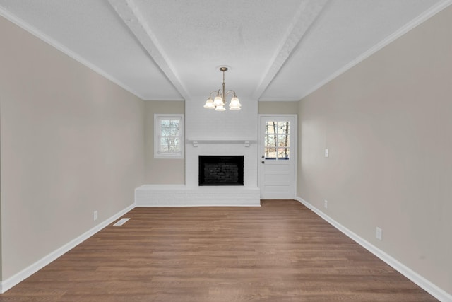 unfurnished living room with crown molding, an inviting chandelier, a fireplace, wood-type flooring, and a textured ceiling