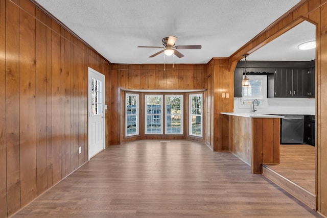 kitchen with hanging light fixtures, dishwasher, kitchen peninsula, and light hardwood / wood-style flooring