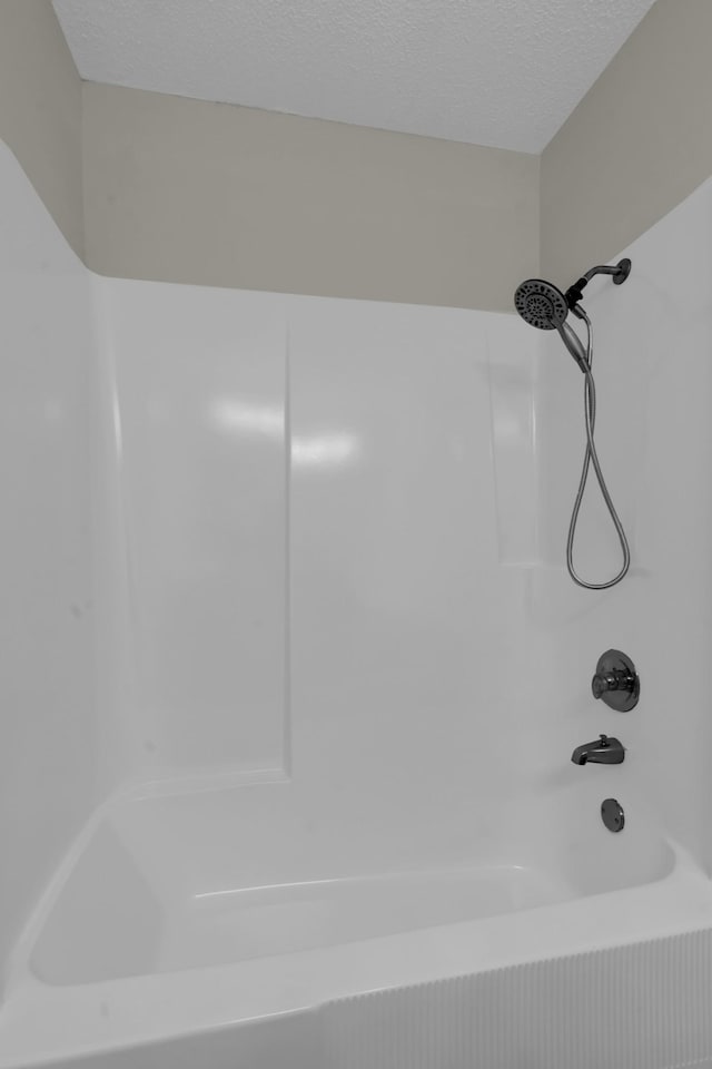 bathroom with shower / washtub combination and a textured ceiling