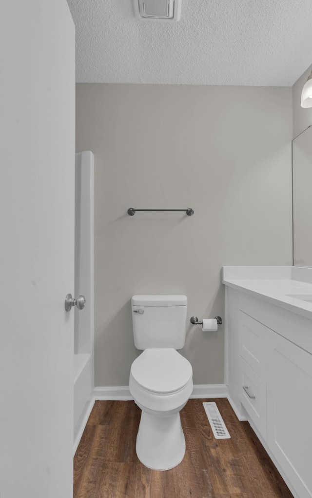 bathroom with vanity, hardwood / wood-style floors, a textured ceiling, and toilet