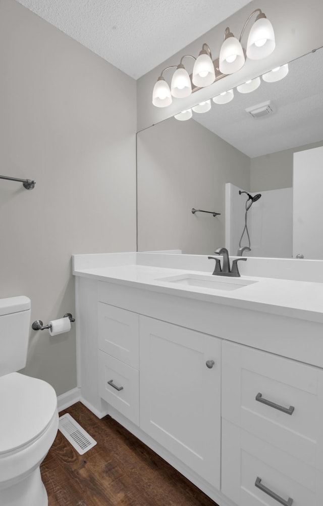 bathroom with wood-type flooring, vanity, a textured ceiling, and toilet