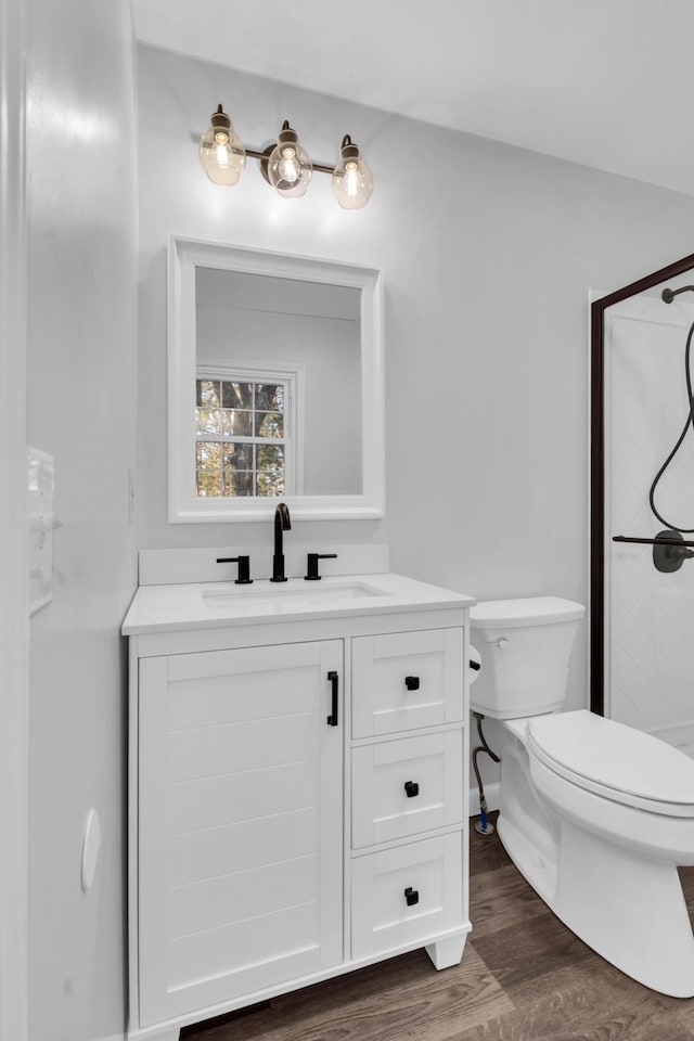 bathroom featuring vanity, hardwood / wood-style floors, walk in shower, and toilet