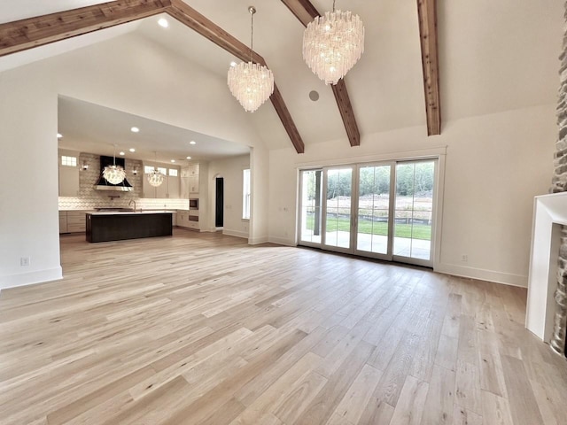 unfurnished living room with beam ceiling, light hardwood / wood-style flooring, high vaulted ceiling, and a chandelier