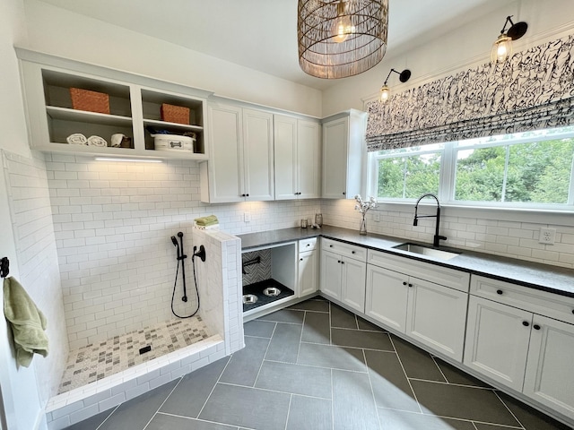 kitchen featuring white cabinetry, sink, dark tile patterned flooring, and decorative backsplash