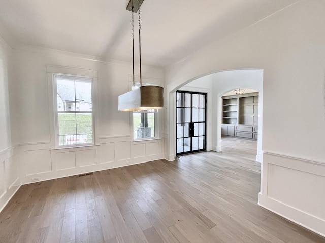 unfurnished dining area featuring built in shelves and hardwood / wood-style floors