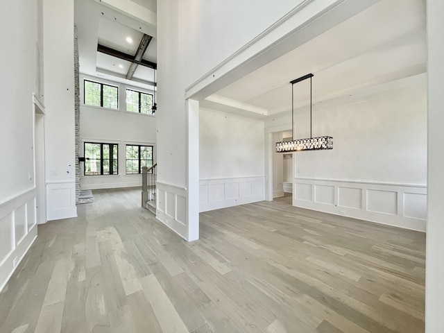 interior space featuring coffered ceiling, beam ceiling, and light wood-type flooring