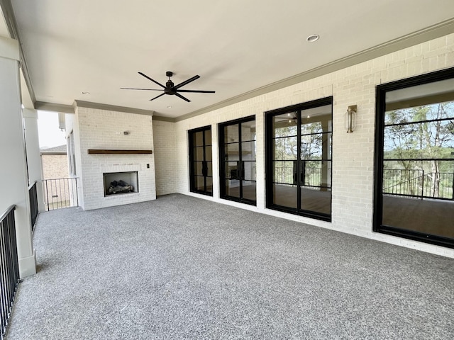 unfurnished living room with exterior fireplace, brick wall, carpet, and plenty of natural light