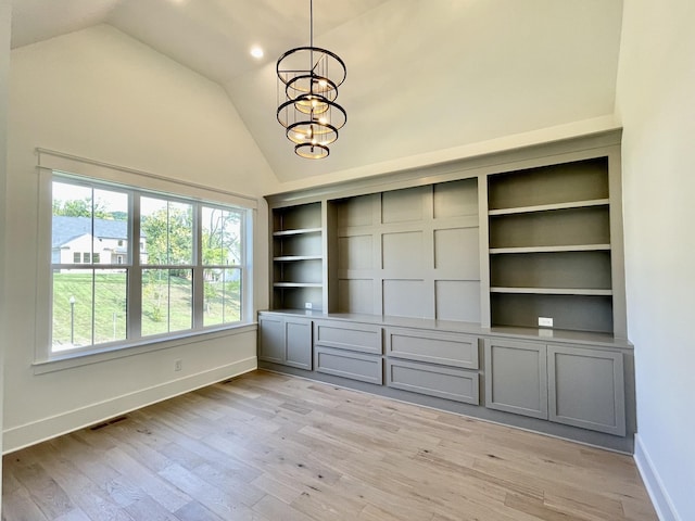 interior space with high vaulted ceiling, light wood-type flooring, a chandelier, and built in shelves