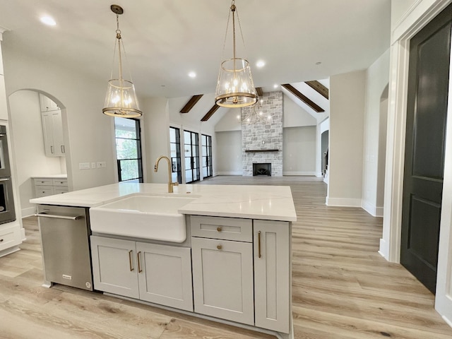 kitchen featuring sink, a large fireplace, hanging light fixtures, and a center island with sink