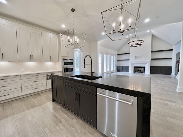 kitchen with white cabinetry, appliances with stainless steel finishes, a kitchen island with sink, and sink