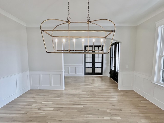 unfurnished dining area featuring crown molding, french doors, and light wood-type flooring