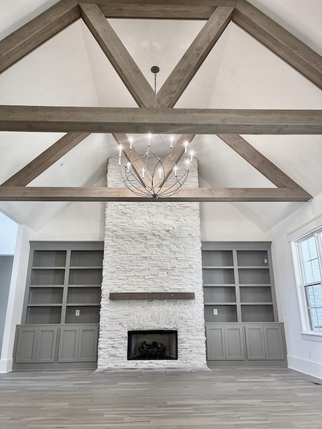 unfurnished living room featuring beamed ceiling, a fireplace, high vaulted ceiling, and a notable chandelier