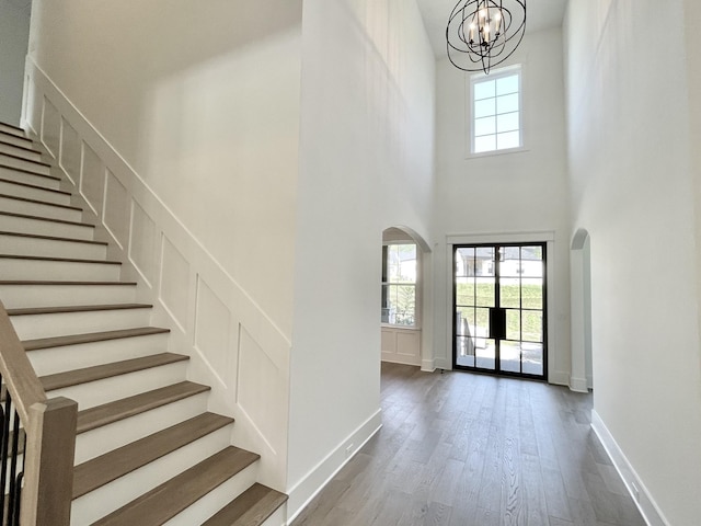 entryway with hardwood / wood-style floors, a chandelier, a healthy amount of sunlight, and a high ceiling