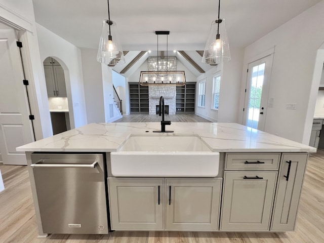 kitchen with sink, a kitchen island with sink, and light stone counters