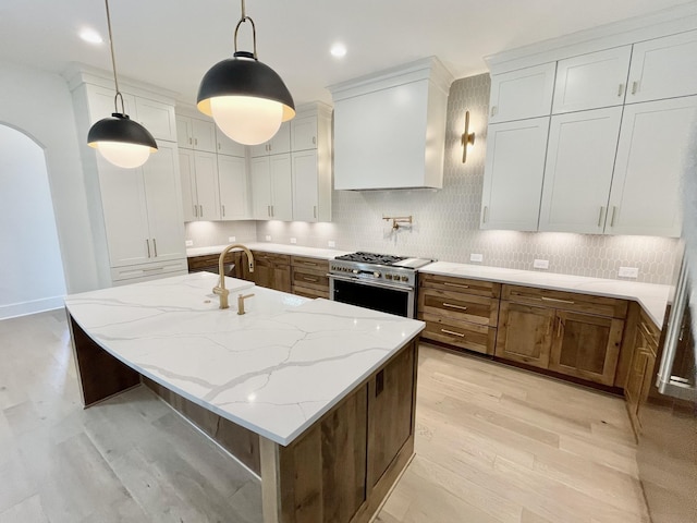 kitchen with hanging light fixtures, high end stove, and white cabinets