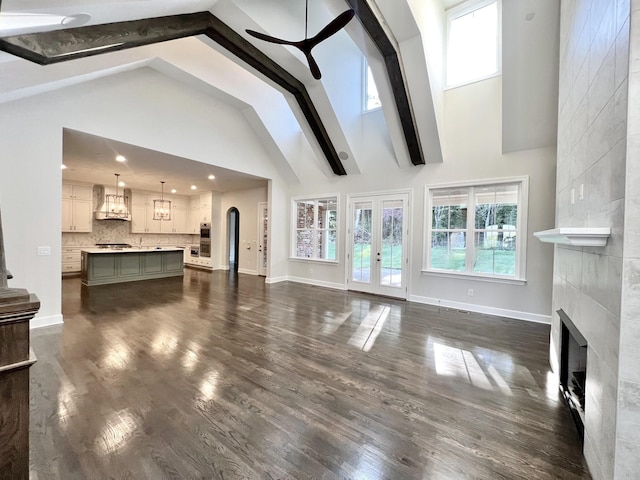 living room with dark hardwood / wood-style floors, high vaulted ceiling, a fireplace, ceiling fan, and beam ceiling