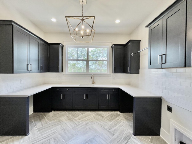 kitchen with sink, pendant lighting, a chandelier, and decorative backsplash