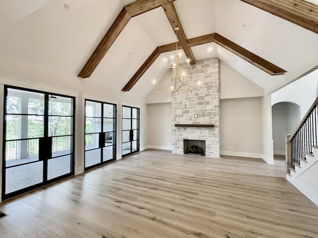 unfurnished living room featuring light hardwood / wood-style flooring, a fireplace, high vaulted ceiling, and a chandelier