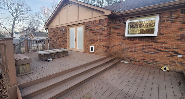 wooden terrace with a fire pit and french doors