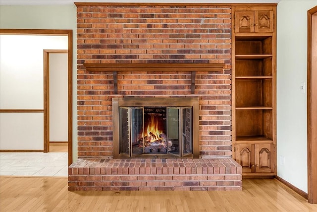 details featuring hardwood / wood-style floors, built in features, and a brick fireplace