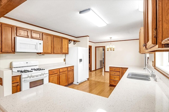 kitchen with pendant lighting, sink, white appliances, crown molding, and kitchen peninsula