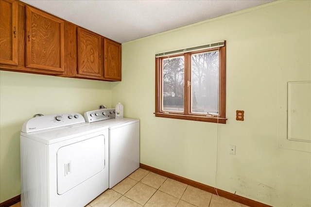 clothes washing area with cabinets, light tile patterned flooring, and washer and clothes dryer