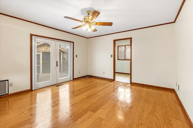 empty room featuring light hardwood / wood-style flooring, a wealth of natural light, ornamental molding, and french doors