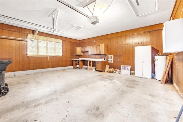 garage with a garage door opener, water heater, and wood walls