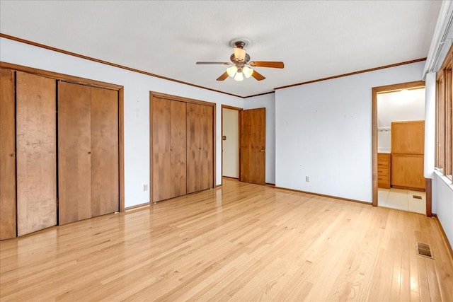 unfurnished bedroom with two closets, ornamental molding, ceiling fan, and light wood-type flooring