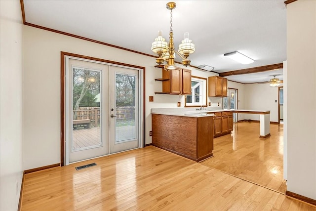 kitchen with pendant lighting, sink, a notable chandelier, french doors, and light wood-type flooring