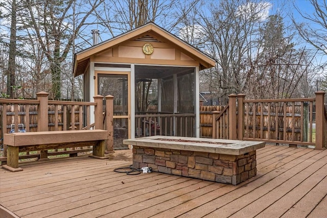 wooden terrace featuring an outdoor fire pit and a sunroom