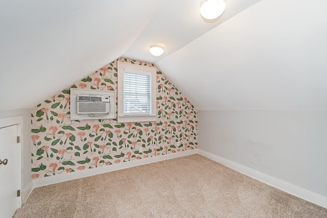 additional living space with a wall mounted air conditioner, vaulted ceiling, and carpet