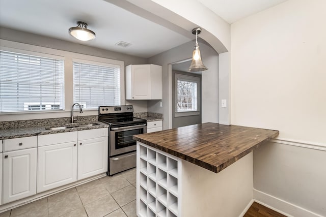 kitchen with butcher block countertops, white cabinetry, sink, hanging light fixtures, and electric range