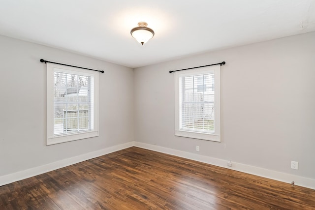 empty room featuring a wealth of natural light and dark hardwood / wood-style floors