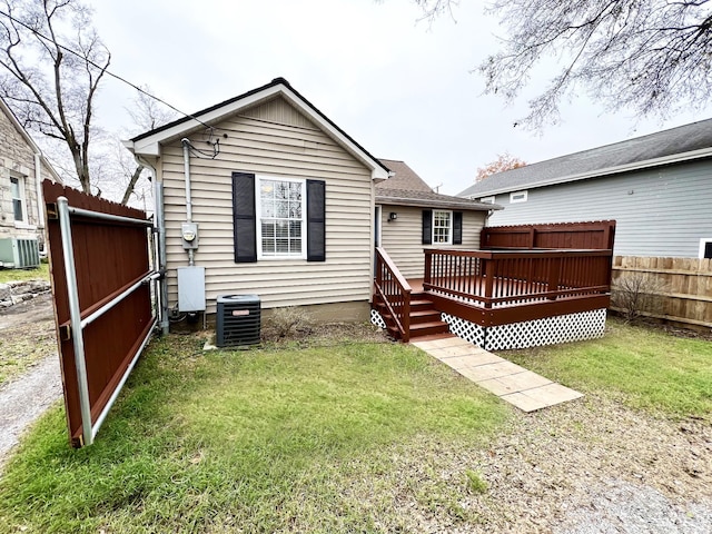 rear view of property with a yard, central AC unit, and a deck