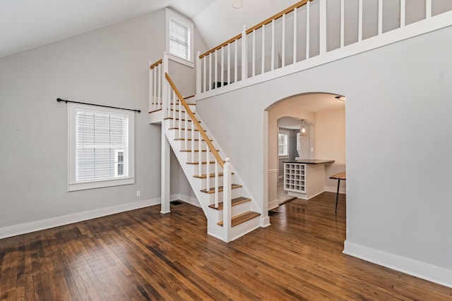 stairs featuring hardwood / wood-style floors and high vaulted ceiling