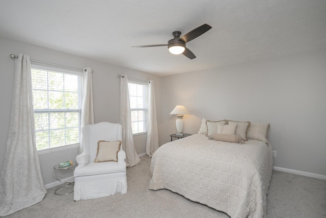 bedroom featuring ceiling fan, light carpet, and a textured ceiling