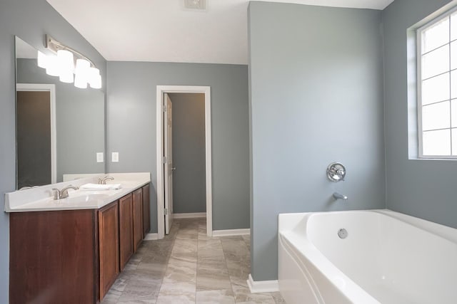 bathroom with a washtub, vanity, and plenty of natural light