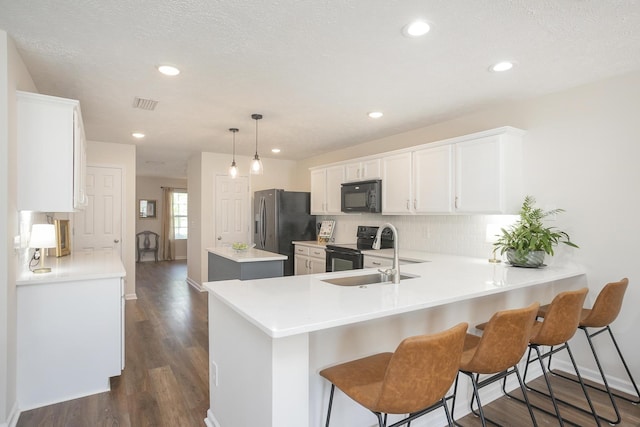 kitchen with white cabinetry, tasteful backsplash, hanging light fixtures, kitchen peninsula, and black appliances