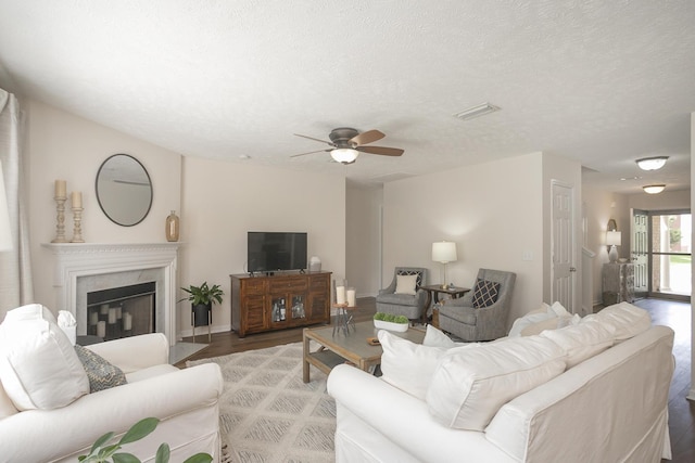 living room with hardwood / wood-style flooring, ceiling fan, a premium fireplace, and a textured ceiling