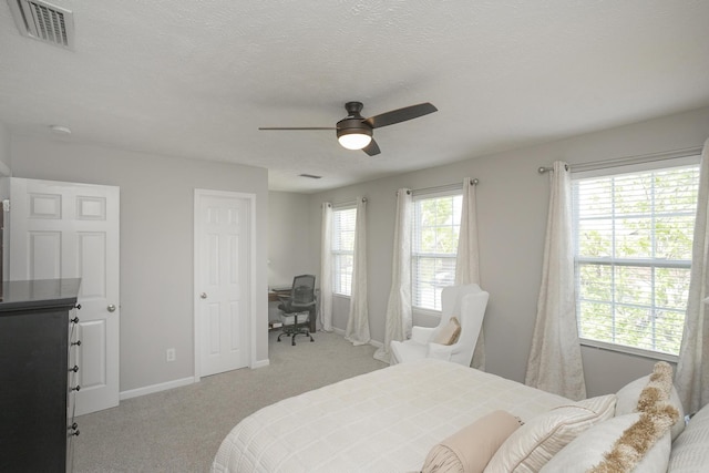 bedroom with ceiling fan, light colored carpet, and a textured ceiling