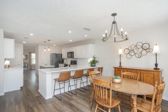 dining room with an inviting chandelier, dark hardwood / wood-style floors, and a textured ceiling