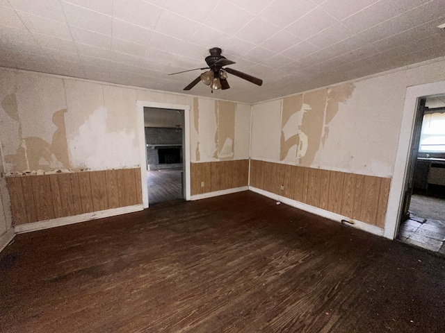 empty room with dark wood-style floors, a wainscoted wall, and wood walls