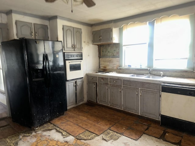 kitchen featuring light countertops, white appliances, a healthy amount of sunlight, and a sink