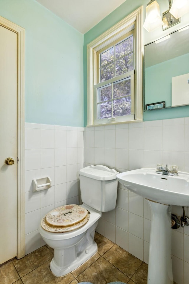 bathroom with tile patterned floors, toilet, and tile walls