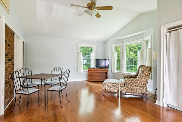 dining area featuring hardwood / wood-style flooring, ceiling fan, lofted ceiling, and brick wall