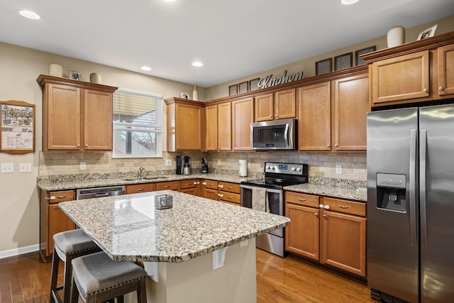 kitchen with appliances with stainless steel finishes, a kitchen breakfast bar, sink, and a kitchen island