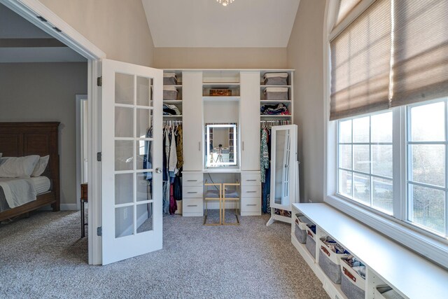 walk in closet featuring french doors, lofted ceiling, and carpet flooring