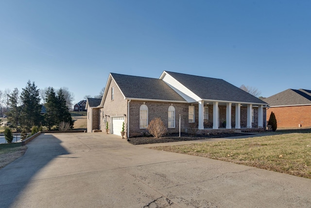 view of front of house featuring a garage, a front lawn, and covered porch