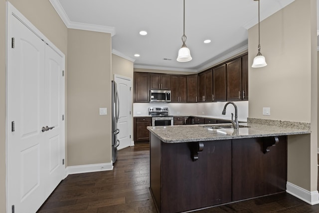 kitchen with appliances with stainless steel finishes, sink, pendant lighting, and kitchen peninsula